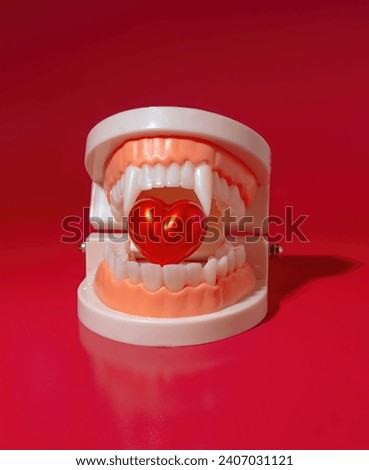 A Vampire Mouth with Sharp Fangs Biting on a Bright Red Heart on a Red Background