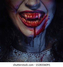 Vampire smile demon woman laughing with big fangs full of blood, image for halloween