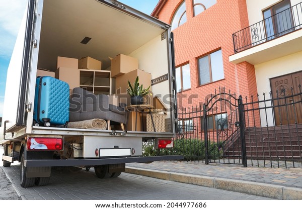 Van full of\
moving boxes and furniture near\
house