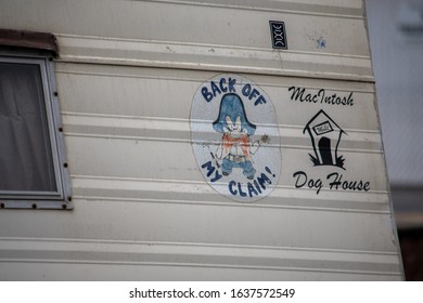 Van Nuys, California / USA  - January 20, 2020: A Back Off My Claim sign and MacIntosh Dog House sign on a mobile home parked at the sidewalk near the homeless camp adjacent to 8100 Haskell Ave.