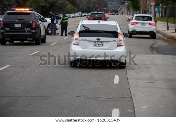 Van Nuys, California / USA  - January 19,
2020: Traffic passes by the scene of a traffic accident
investigation in front of 6750 Balboa Blvd, with police and tow
truck personnel in the
background.