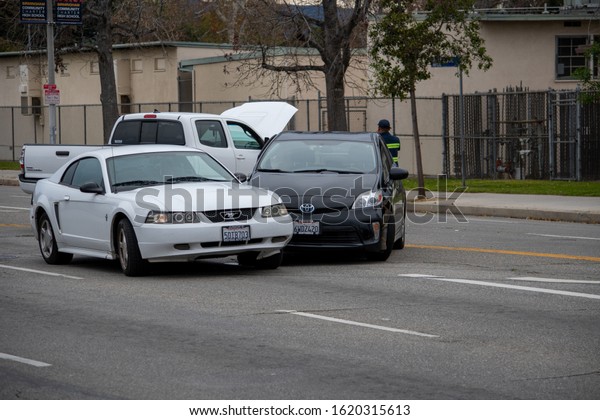 Van Nuys,\
California / USA  - January 19, 2020: A white Ford Mustang and\
black Toyota Prius sit in the middle of the road after an accident\
in front of 6750 Balboa\
Blvd.