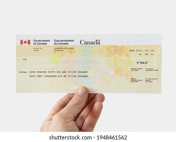 Vancouver, BC - Canada - April 02, 2021: Man Holding Canada Government Tax Refund Cheque On A White Background