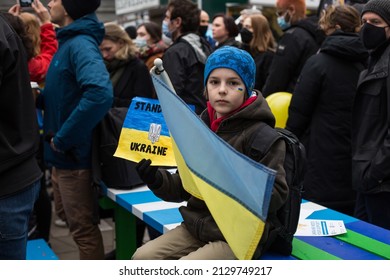 Vancouver, BC, Canada, February 26, 2022, A child with Ukrainian flag on his cheek and the sign Stand With Ukraine at the antiwar protest in the centre of downtown