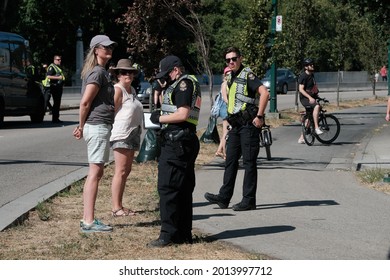Vancouver, BC, Canada - July 24, 2021:  A Vancouver Police officer processes arrested activists at an "Extinction Rebellion" climate change protest in front of the Burrard Street Bridge