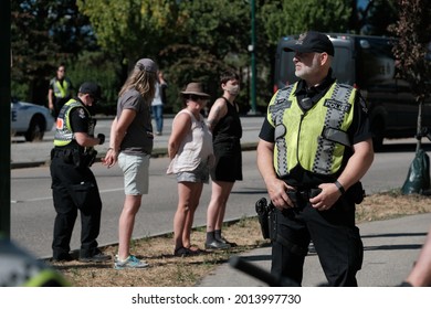 Vancouver, BC, Canada - July 24, 2021:  Vancouver Police officer stands in front of arrested activists at an "Extinction Rebellion" climate change protest in front of the Burrard Street Bridge