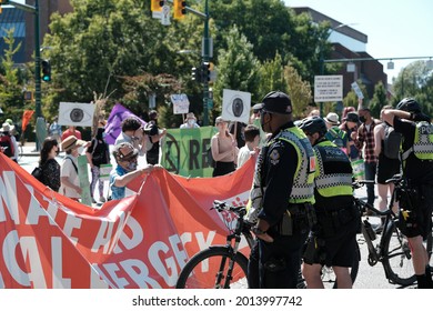 Vancouver, BC, Canada - July 24, 2021:  Vancouver Police officer stands in front of a crowd at an "Extinction Rebellion" climate change protest in front of the Burrard Street Bridge