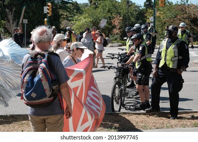 Vancouver, BC, Canada - July 24, 2021:  Line of protesters approach a line of Vancouver Police officers at an "Extinction Rebellion" climate change protest in front of the Burrard Street Bridge