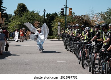 Vancouver, BC, Canada - July 24, 2021:  A woman dances in from of a line of Vancouver Police officers at an "Extinction Rebellion" climate change protest in front of the Burrard Street Bridge