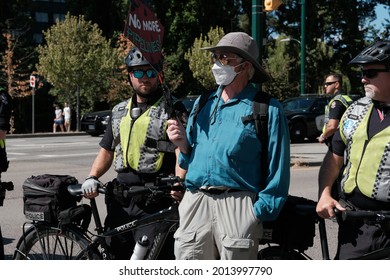 Vancouver, BC, Canada - July 24, 2021:  Elderly activist holds a sign in from of police officers at an "Extinction Rebellion" climate change protest in front of the Burrard Street Bridge