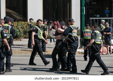 Vancouver, BC, Canada - July 24, 2021:  Vancouver Police officers carry away an activist from a blockade at an "Extinction Rebellion" climate change protest in front of the Burrard Street Bridge