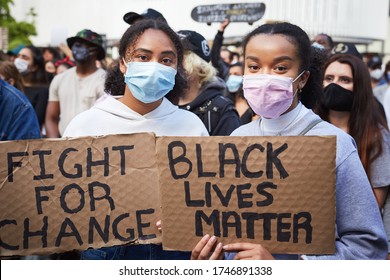 Vancouver BC, Canada, May 31 2020: Portrait of two young women of dark skin colour with a face mask holding cardboard banners "black lives matter"