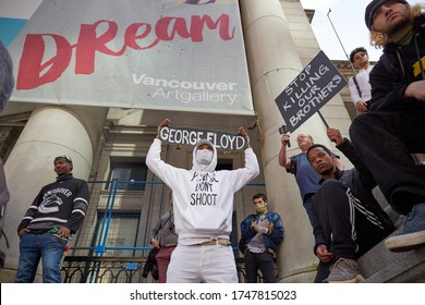 Vancouver BC, Canada, May 31 2020: Young Man Dressed In All White Clothes With A Skateboard Above His Head With George Floyd Name On It.