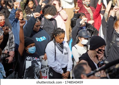 Vancouver BC, Canada, May 31 2020: Young brown girl is looking down and being quiet for the death of George Floyd for one minute at the rally, along with other protesters with their hands and fists up