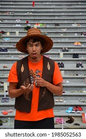 Vancouver, B.C. Canada. May 31, 2021. Indigenous Man In Orange Shirt Praying, Singing And Talking In Front Of Steps With Symbolic Shoes On Steps Plus Flowers And Toys.