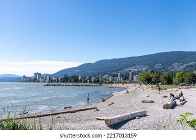 Vancouver, BC, Canada-August 2022; Panoramic View Over The Ambleside Beach In West Vancouver With People On Beach And Squamish Nation Welcome Figure In Background On A Sunny Day