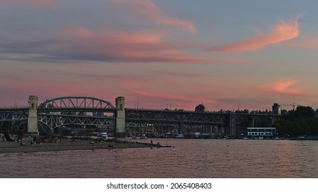 Vancouver, British Columbia, Canada - 09-24-2021: Stunning view of people enjoying the evening at Sunset Beach, Vancouver downtown with Burrard Street Bridge and pink colored sky.