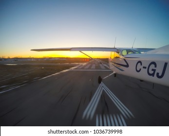 Vancouver, British Columbia, Canada - February 22, 2018: Small Airplane, Cessna 172, is landing on a runway during a vibrant sunset.