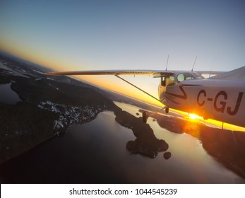 Vancouver, British Columbia, Canada - February 22, 2018: Small Airplane, Cessna 172, is flying over the city during a vibrant sunset.