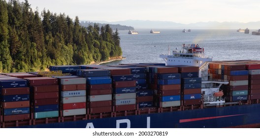 Vancouver, British Columbia, Canada - June 26, 2021: Aerial View from Above of a Cargo Ship arriving to the Port on the West Coast Pacific Ocean during a sunny evening.