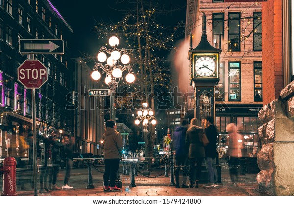 Vancouver, British Columbia - Dec 3, 2019 : The\
famous Steam Clock in Gastown in Vancouver city with cars light\
trails at night