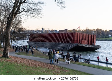 VANCOUVER, CANADA - 11-16-2021 - People walking in front of the Beached Barge on Sunset Beach 
 with Burrard Street Bridge in the background after a devastating storm the previous day