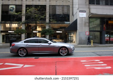 VANCOUVER, CANADA - Apr 03, 2022: A long exposure shot of a BMW 640 gray car in the street downtown in daylight in Vancouver, Cana