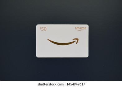 Vancouver, Canada - July 18, 2019:  Amazon Gift Card on blue background, white and gold $50 gift card for Amazon.com website