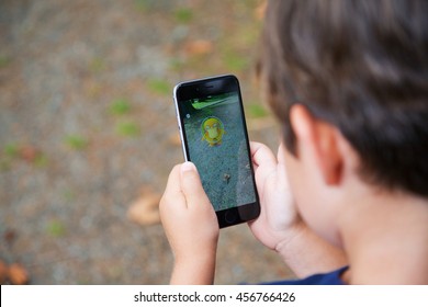 VANCOUVER, CANADA - JULY 22, 2016: A Young Boy Outside Playing Pokemon Go On A Smart Phone.