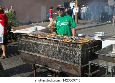 VANCOUVER, CANADA - JUNE 09, 2014: Italian Day In Commercial Drive.Crowd Of People Walking. Man Cooking Fresh Fish On Barbecue Grill Street.