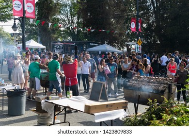 VANCOUVER, CANADA - JUNE 09, 2014: Italian Day In Commercial Drive.Crowd Of People Walking. Man Cooking Chicken On Barbecue Grill Street.