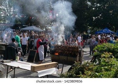 VANCOUVER, CANADA - JUNE 09, 2014: Italian Day In Commercial Drive.Crowd Of People Walking. Man Cooking Chicken On Barbecue Grill Street.