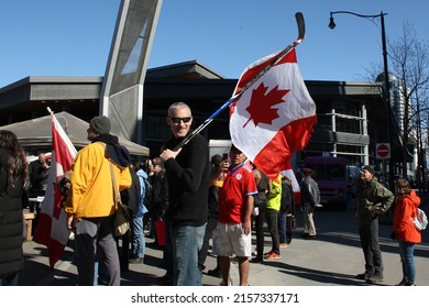 VANCOUVER, CANADA - Mar 19, 2022: A Man Carrying Canadian Flag On Ice Hockey Stick In Downtown Vancouver, British Columbia, Canada