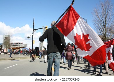 VANCOUVER, CANADA - Mar 19, 2022: A Man Carrying Canadian Flag On Ice Hockey Stick In Downtown Vancouver, British Columbia, Canada