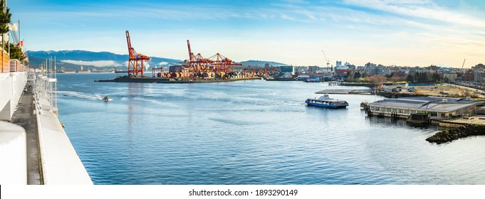Vancouver Harbour panorama early mornings, on a sunny day. Waterfront city skyline with industry. A seabus ferry is leaving the waterfront station. Industrial cranes with cargo containers and tanker.
