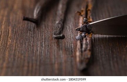 Vanilla beans and seed pods with knife on wooden background.  Preparing vanilla as baking ingredient.