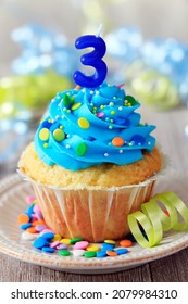 vanilla birthday cupcake for a 3 year old, with blue frostig and colorful sprinkles