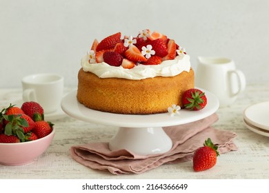 vanilla cake with cream cheese frosting and fresh strawberries on cake stand - Shutterstock ID 2164366649