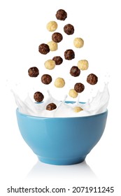 Vanilla and chocolate corn balls falling in blue bowl. Breakfast cereal with splashing milk isolated on white background