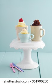 Vanilla And Chocolate Mug Cakes With Frosting  And Raspberries On A Cake Stand