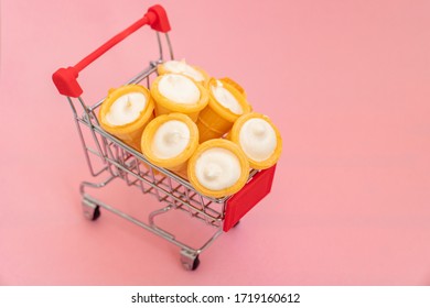 Vanilla Cream In Wafer Cup In A Shopping Cart A Small Toy. Vanilla Ice Cream Cone On Pink Color Background. Candy Bar And Cake Pops. Holiday Treats. Sweet Tooth. Candy Shop. 