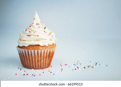 Vanilla Cup Cake With White Icing And Candies On Top