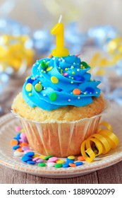 Vanilla cupcake with candle and blue vanilla frosting celebrating a birthday