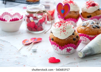 Vanilla cupcakes with chocolate chips and whipped cream frosting sprinkled with red colored sugar on the white background - Powered by Shutterstock