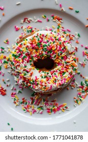 Vanilla Donut With Rainbow Sprinkles On White Plate