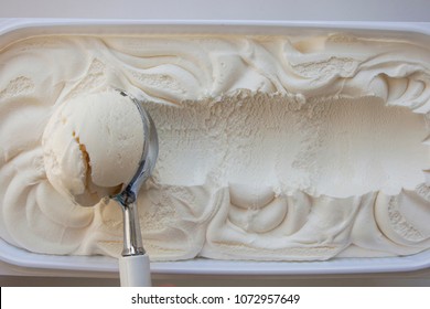 Vanilla ice cream Flat lay. Top view. Spoon for ice cream takes a little out of the package. Macking ball of ice cream. Space for text. - Shutterstock ID 1072957649