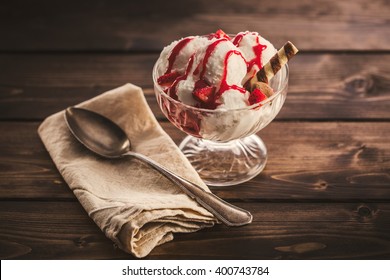 Vanilla Ice Cream With Syrup And Sliced Strawberry In Ramekin On Wooden Table. From Above