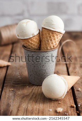 vanilla ice cream with a waffle cone in a ceramic glass on a wooden table