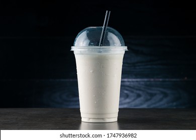 Vanilla Milk Shake In Plastic Glass On A Dark Background. Vanilla Milkshake In Takeaway Cup