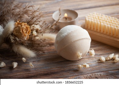 Vanilla peach aroma bath bombs in spa composition with dry flowers. Aromatherapy arrangement, zen still life with lit candles and body brushes
